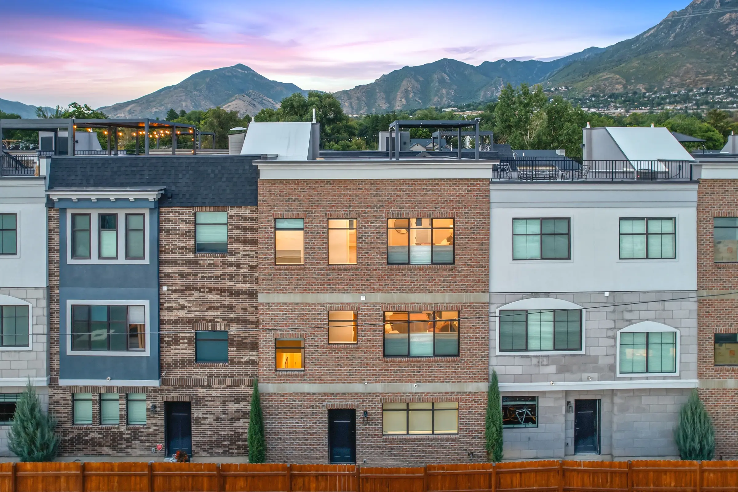 The home at dusk below the Wasatch, rooftop decks and lit windows